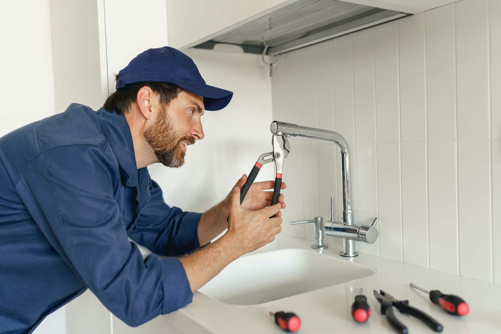 professional-plumber-in-blue-uniform-fixing-broken-water-tap-in-kitchen-repair-service-concept.jpg